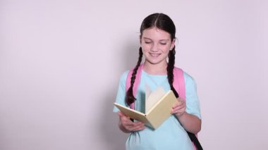 Açık gri arkaplan üzerine kitap okuyan hoş bir kız.