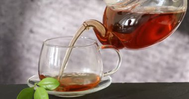 Siyah masada çaydanlıktan fincana sıcak çay dökmek, yakın plan.