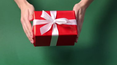 Yeşil arka planda hediye kutusunu tutan kadın, yakın plan. Mutlu Noeller ve mutlu yıllar.