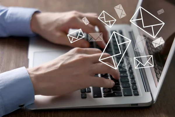 Masadaki bilgisayardan e-posta gönderen ya da alan adam, yakın plan. Ekranda uçuşan harfler