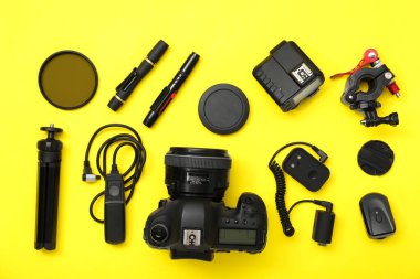 Sarı arka planda profesyonel fotoğrafçı ekipmanı var.