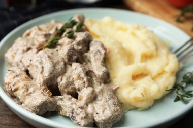 Ahşap masada servis edilen patates püresi ve kekik ile nefis sığır stroganoff, yakın plan.