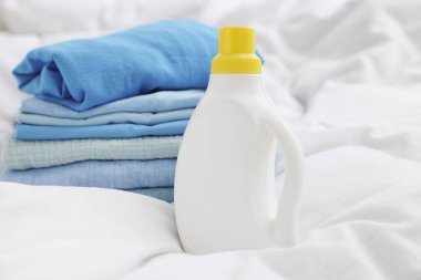 Yatakta temiz çamaşır ve deterjan, yakın plan.