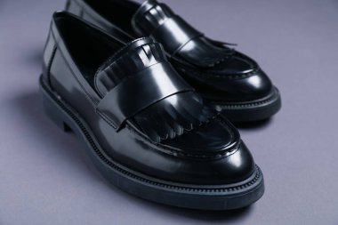 Gri arka planda şık siyah ayakkabılar, yakın plan.