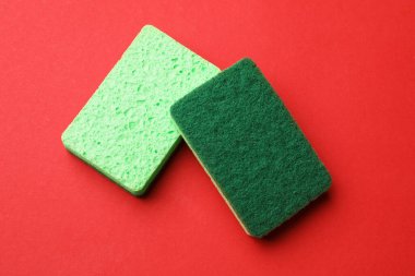 Kırmızı arka planda mutfak süngerleri, üst görünümde