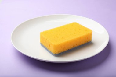 Menekşe arka planda mutfak süngeri ve tabağı, yakın plan.