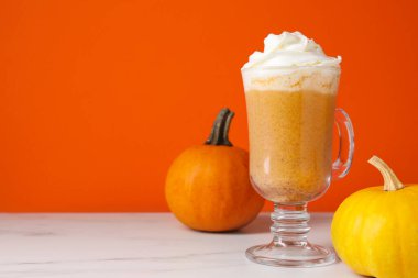 Krem şantili ve taze sebzeli balkabaklı latte turuncu arka planda, yakın plan. Metin için boşluk