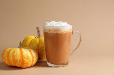 Cam bardakta kremalı balkabaklı latte ve bej arka planda taze sebzeler, yakın plan. Metin için boşluk