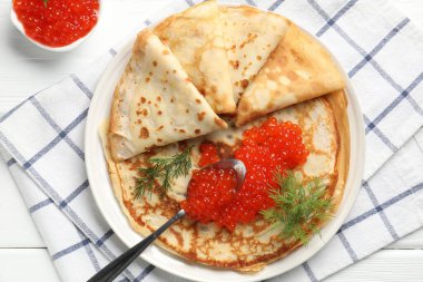 Beyaz ahşap masada kırmızı havyarlı leziz krepler.