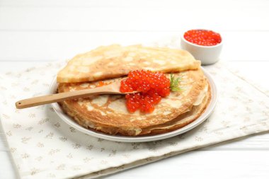 Beyaz ahşap masada kırmızı havyarlı leziz krepler, yakın plan.