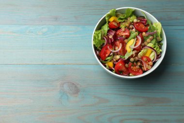 Açık mavi ahşap masada mercimek ve sebzelerle nefis bir salata, üst manzara. Metin için boşluk