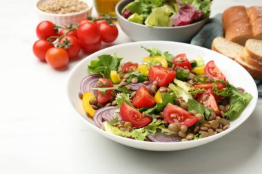 Beyaz masada sunulan mercimek ve sebzeli leziz salata.