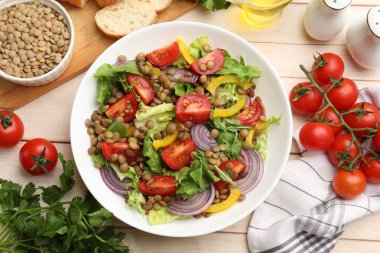 Lezzetli mercimek salatası ve malzemeler açık ahşap masada, düz yatıyordu.