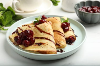 Kiraz reçeli ve çikolata ile servis edilen leziz krepler, yakın plan.