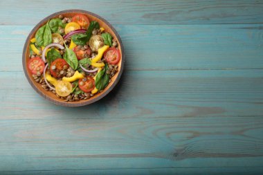 Açık mavi ahşap masada mercimek ve sebzeli leziz salata, üst manzara. Metin için boşluk