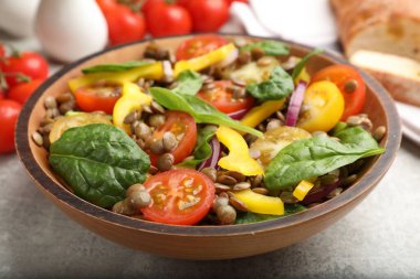 Gri masada mercimek ve sebzeli lezzetli salata, yakın plan.