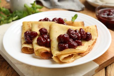 Kirazlı ve naneli leziz krepler ahşap masada servis edilir, yakın plan.