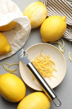 Taze limonlar, keyifli ve zester aletli gri masada, düz yerde.