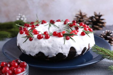 Gri ahşap masada yaban mersinli, biberiyeli ve şenlikli bir Noel pastası. Yakın plan.