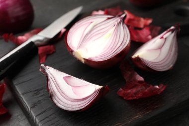 Kabuklu soğan soğanları ve siyah masada bıçak, yakın plan.