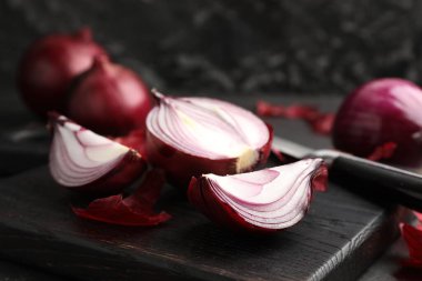 Kabuklu soğan soğanları ve siyah masada bıçak, yakın plan.