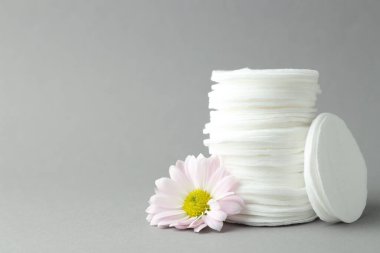 Açık gri arka planda temiz pamuk pedleri ve çiçek yığını, yakın plan. Metin için boşluk