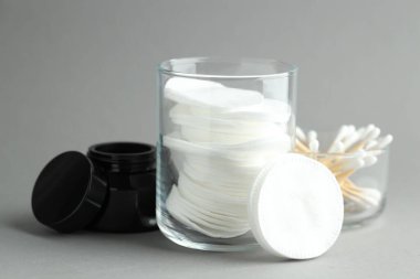 Açık gri arka planda temiz pamuk, bez ve kozmetik ürünler, yakın plan