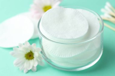 Turkuaz arka planda temiz pamuk pedleri, bezler ve çiçekler, yakın plan