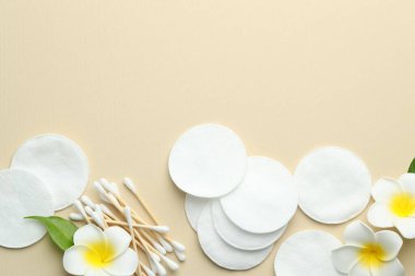 Temiz pamuk pedleri, bej arka planda bezler ve çiçekler, düz yatış. Metin için boşluk