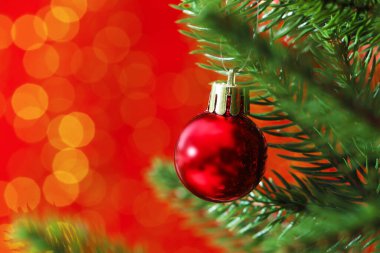 Noel ağacında kırmızı arka planda, bulanık ışıklar, yakın çekim ve yazı için yer olan güzel bir süs. Bokeh etkisi