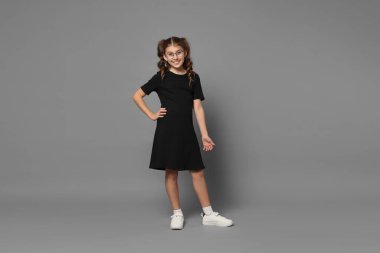 Gri arka planda gülümseyen gözlüklü kız.