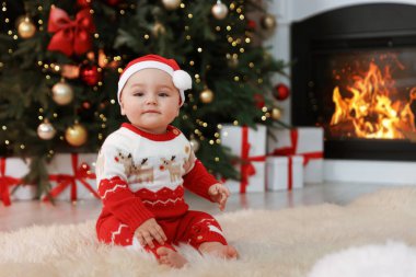 Noel Baba şapkalı şirin bebek, Noel için dekore edilmiş odada, yumuşak halıda. Metin için boşluk