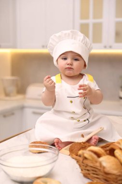 Mutfaktaki açık mermer masada şef üniforması giyen şirin bir bebek.