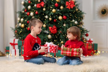 Noel için dekore edilmiş hediye kutularıyla küçük bir çocuk ve kız.