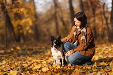 Sonbahar parkında sevimli köpeğini gezdiren bir kadın.