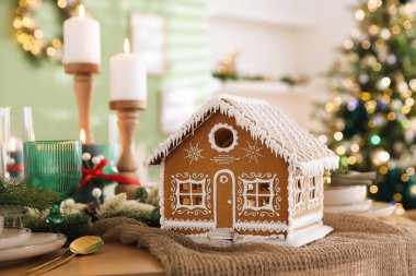 Güzel zencefilli kurabiye evi ve kapalı mekanlı Noel dekoruyla şenlik masası, yakın plan. Bokeh etkisi