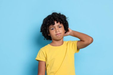 Açık mavi arka planda kafası karışmış küçük bir çocuğun portresi