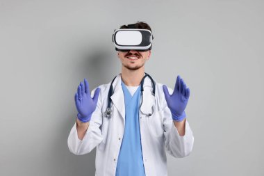 Modern teknoloji. Gri arkaplanda sanal ekran kullanan kulaklıklı bir doktor