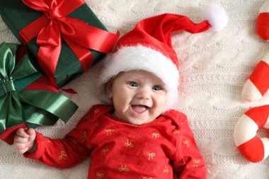 Noel Baba şapkalı bebek ve Noel dekoru yatağın üstünde.