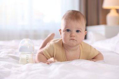 Evde yatağında biberonla beslenen tatlı bir bebek. Metin için boşluk