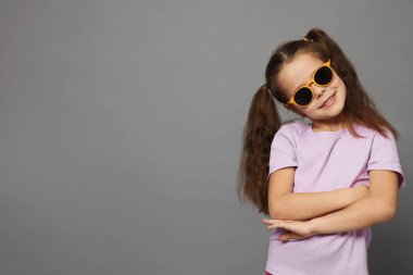 Gri arka planda güneş gözlüklü şirin küçük kız portresi, mesaj için boşluk