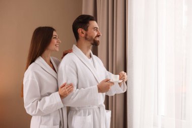 Sabahları evde kahve içen bornozlu mutlu bir çift. Metin için boşluk