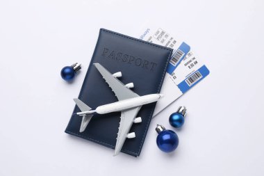 Noel tatili. Biletli pasaport, uçak modeli ve beyaz arka plandaki süsler, düz konum