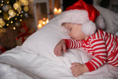Noel pijamalı bebek ve Noel Baba şapkalı evde uyuyan bebek.