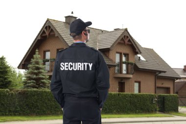 Evin yanında üniformalı bir güvenlik görevlisi var. Özel mülk koruması