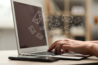 Masadaki bilgisayardan e-posta gönderen ya da alan adam, yakın plan. Ekranda uçuşan harfler