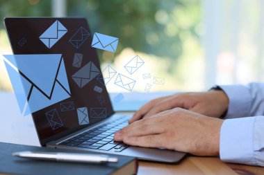 E- posta bildirimi. Masada dizüstü bilgisayar kullanan adam, yakın plan. Ekranda uçuşan harfler