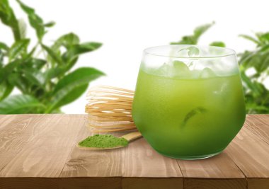 Bardakta buz, çay tozuyla kaşık ve yeşil yapraklara karşı ahşap masada çırpılmış kibrit suyu. Metin için boşluk