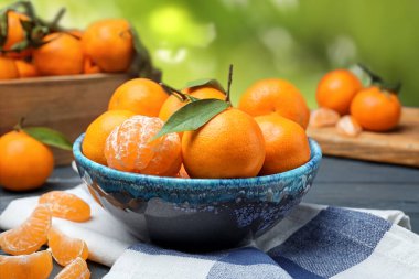 Masada taze, sulu mandalinalar ve bulanık yeşil arka plan.