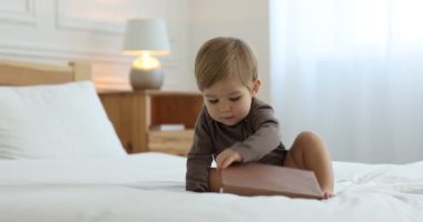 Evinde yerde kitabı olan sevimli küçük bir çocuk.